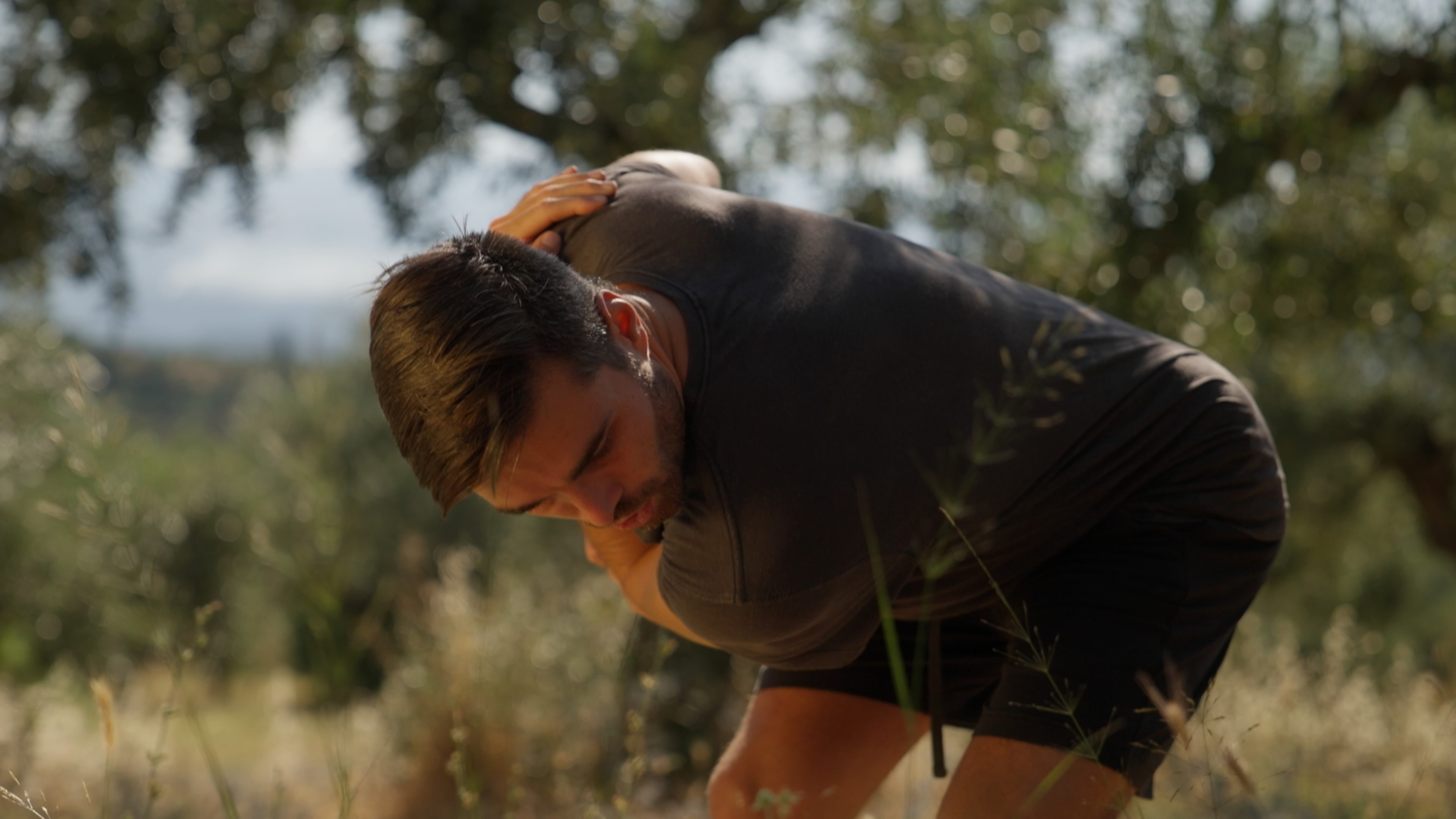 Coach demonstrating a fascial movement outdoors among olive trees